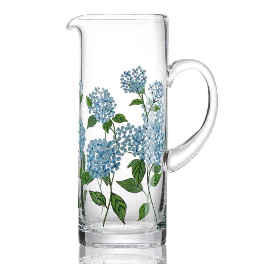 Clear glass pitcher with blue floral design on a white background