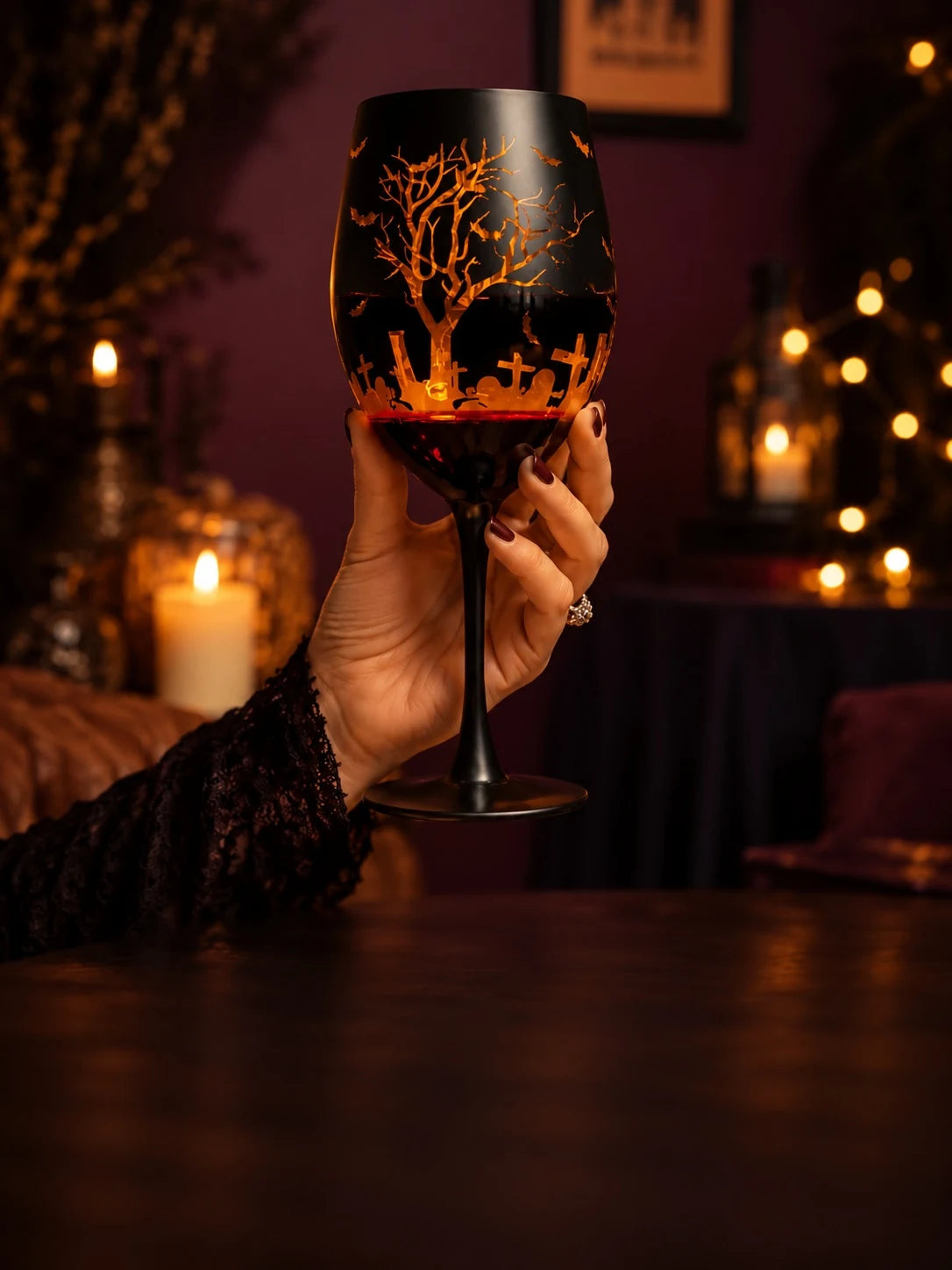 Halloween goblet with orange graveyard design held by candlelight