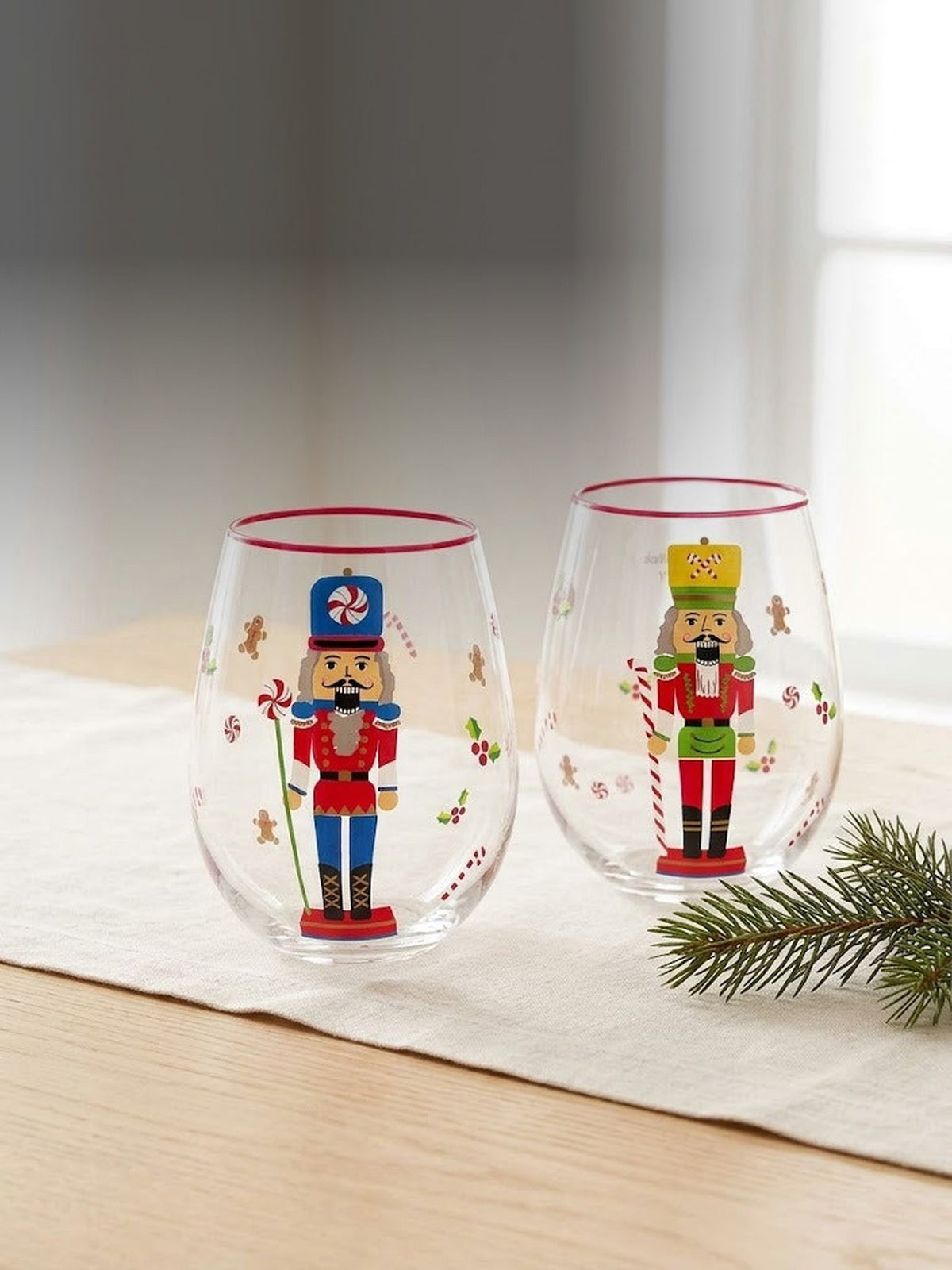 Both hand-painted nutcracker stemless wine glass designs together on a sunlit oak table
