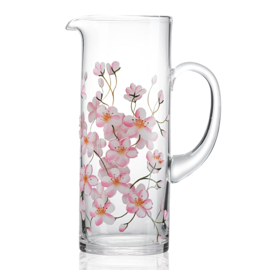 Clear glass pitcher with pink floral cherry blossom design on a white background