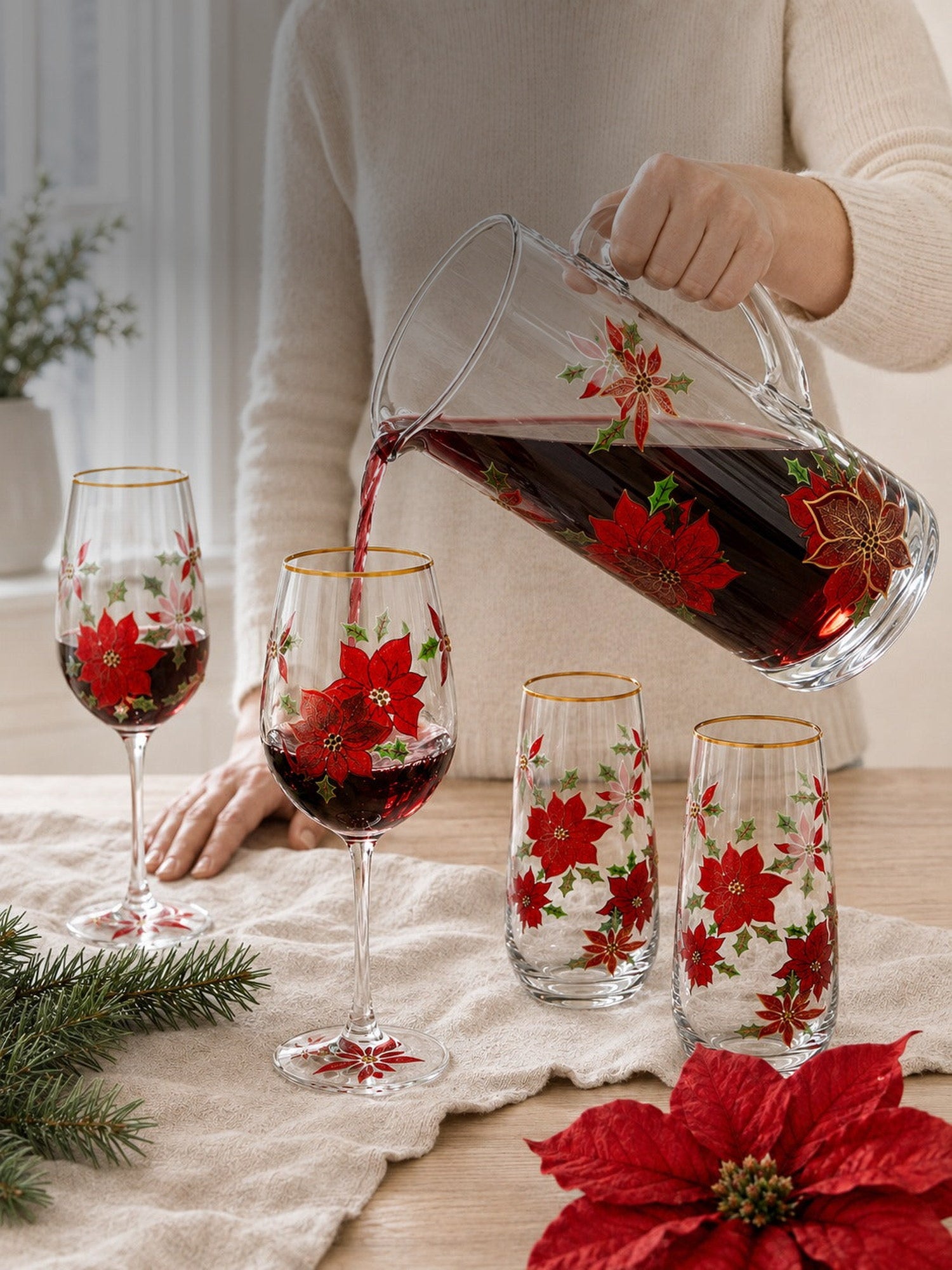 Host pouring red wine from the hand-painted poinsettia pitcher into a matching stemmed wine glass